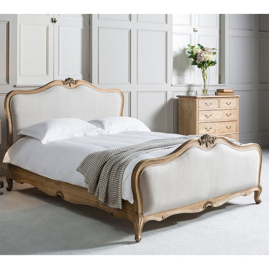 A Holne 5' Linen Upholstered Bed Weathered with an ornate headboard and footboard, available for interior decor at Kikiathome.co.uk.
