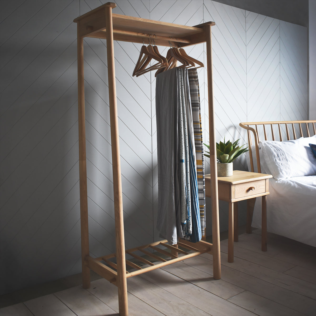 A home furniture piece, the Tigley Open Wardrobe from Kikiathome.co.uk, enhances the interior decor of a bedroom with a bed.
