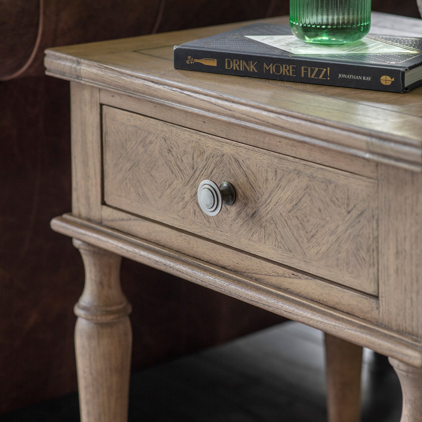 A Belsford 1 Drawer Side Table adorned with a book, serving as interior decor furniture in a home.