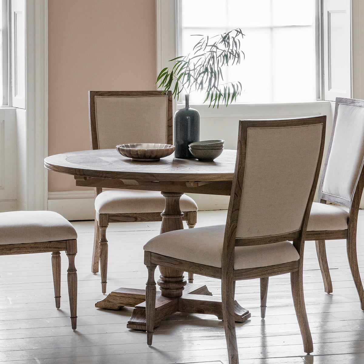 A Belsford Round Extendable Dining Table and four chairs in a room by Kikiathome.co.uk, perfect for home furniture and interior decor.