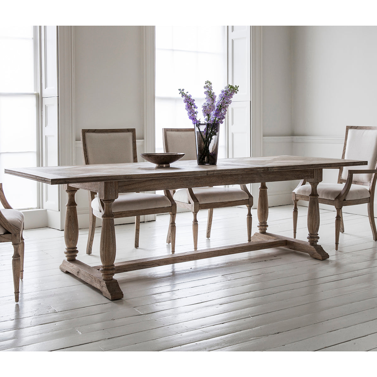 A Belsford Extending Dining Table 2500x1000x750mm with four chairs in a room with white walls from Kikiathome.co.uk, perfect for home furniture and interior