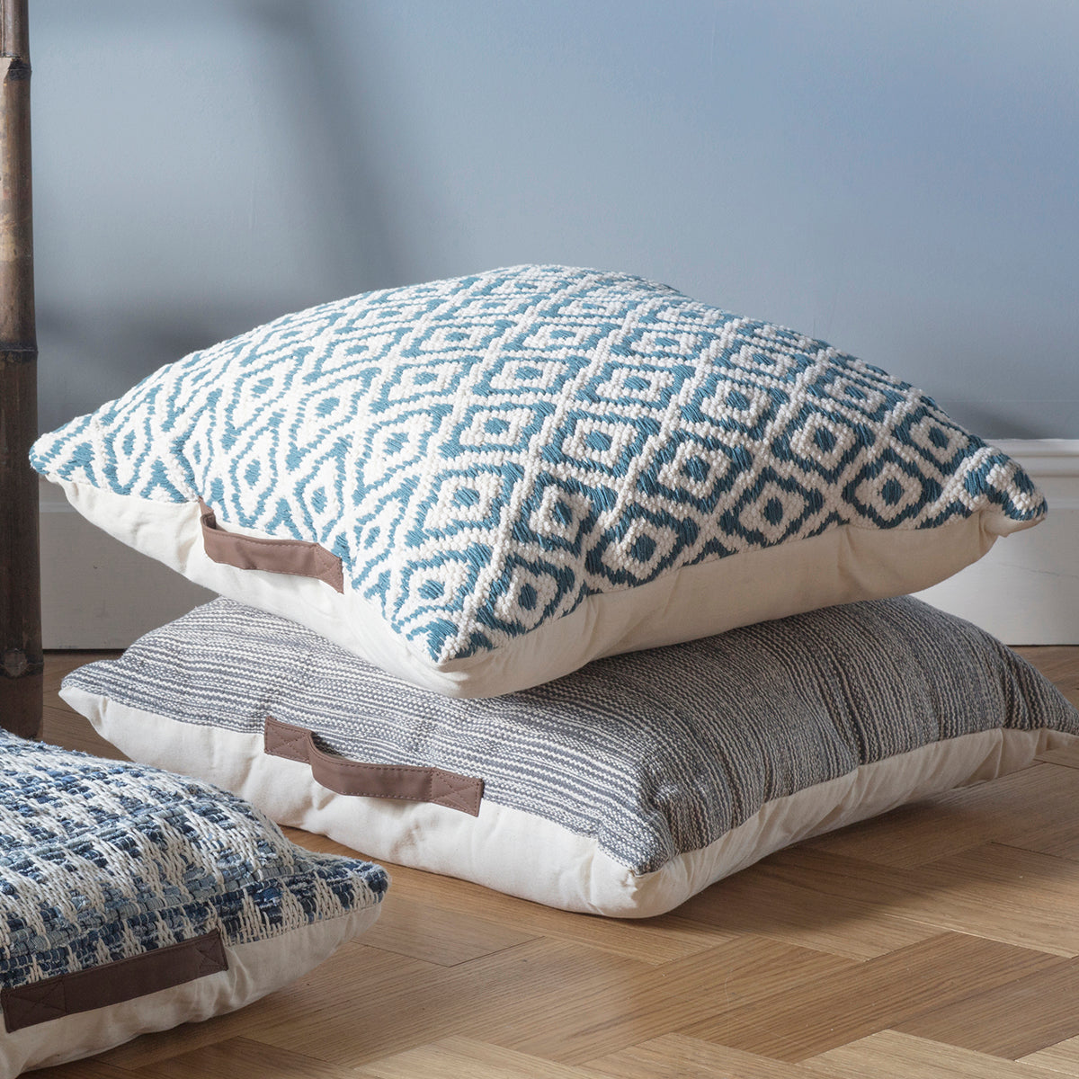 Load image into Gallery viewer, Three Sigtuna teal floor cushions add a touch of interior decor to a wooden floor.
