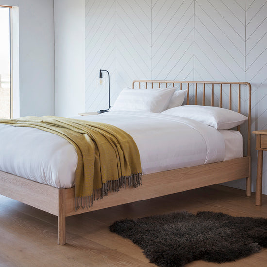 A Tigley 5' Spindle Bed in a bedroom with wood floors and a yellow blanket, combining home furniture and interior decor.