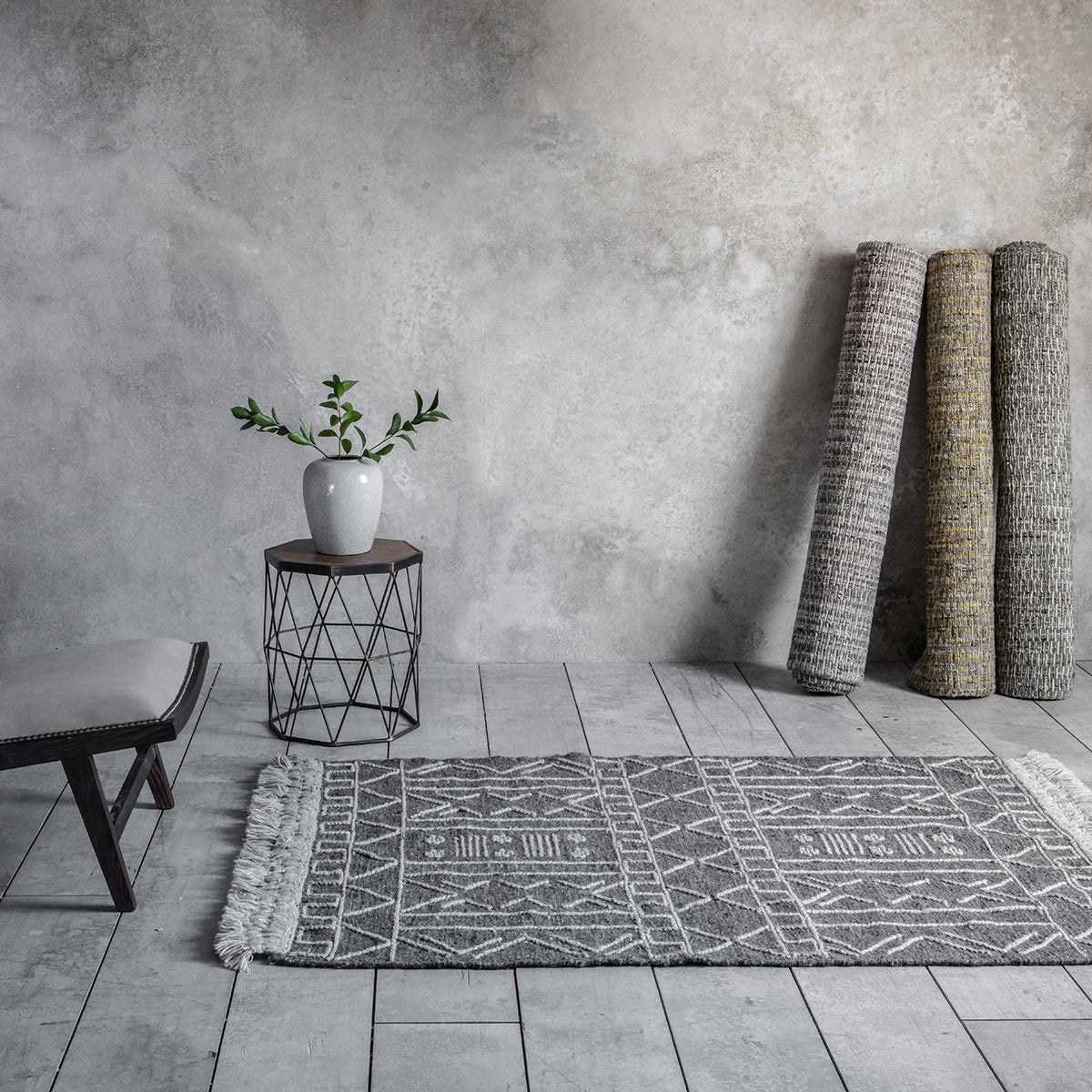 An Aish Rug 1200x1700mm in a concrete room for interior decor.