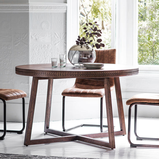 A Dartington Retreat Round Dining Table 1200x1200x750mm with chairs, ideal for interior decor and home furniture, in front of a window, from Kikiathome.co.uk