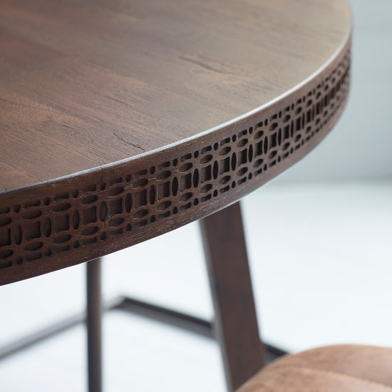 A close up of the Dartington Retreat Round Dining Table with a carved design, perfect for home furniture.