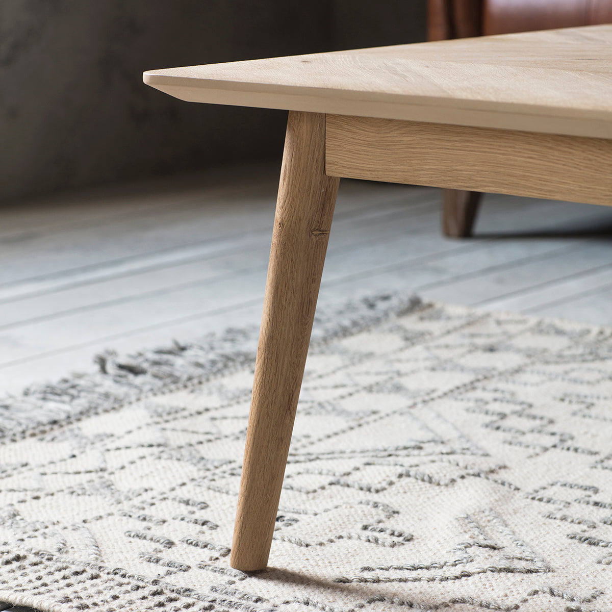 A Kikiathome.co.uk coffee table on a rug next to a leather couch - interior decor.