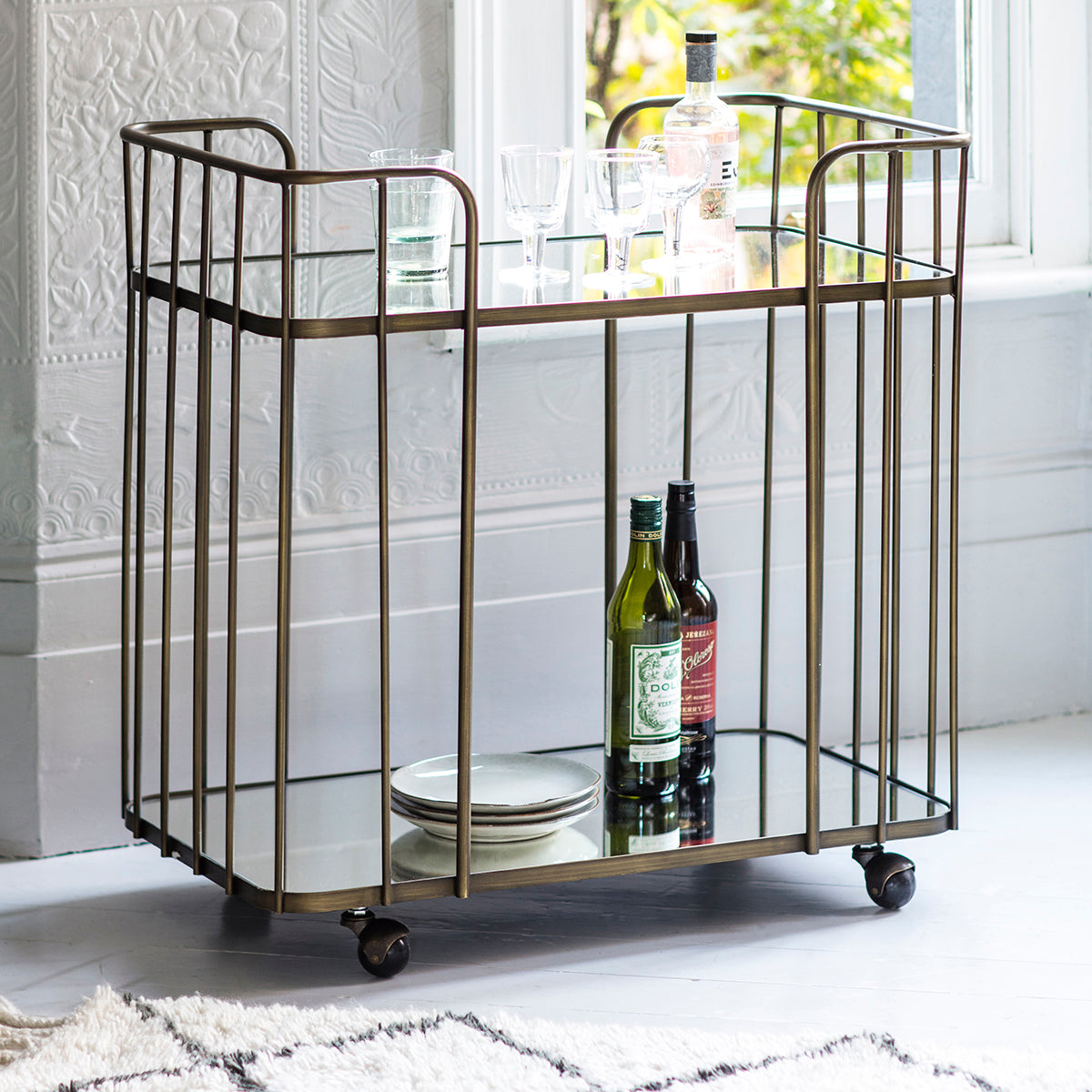 A bronze Verna Drinks Trolley from Kikiathome.co.uk showcasing interior decor with a bottle of wine on top.