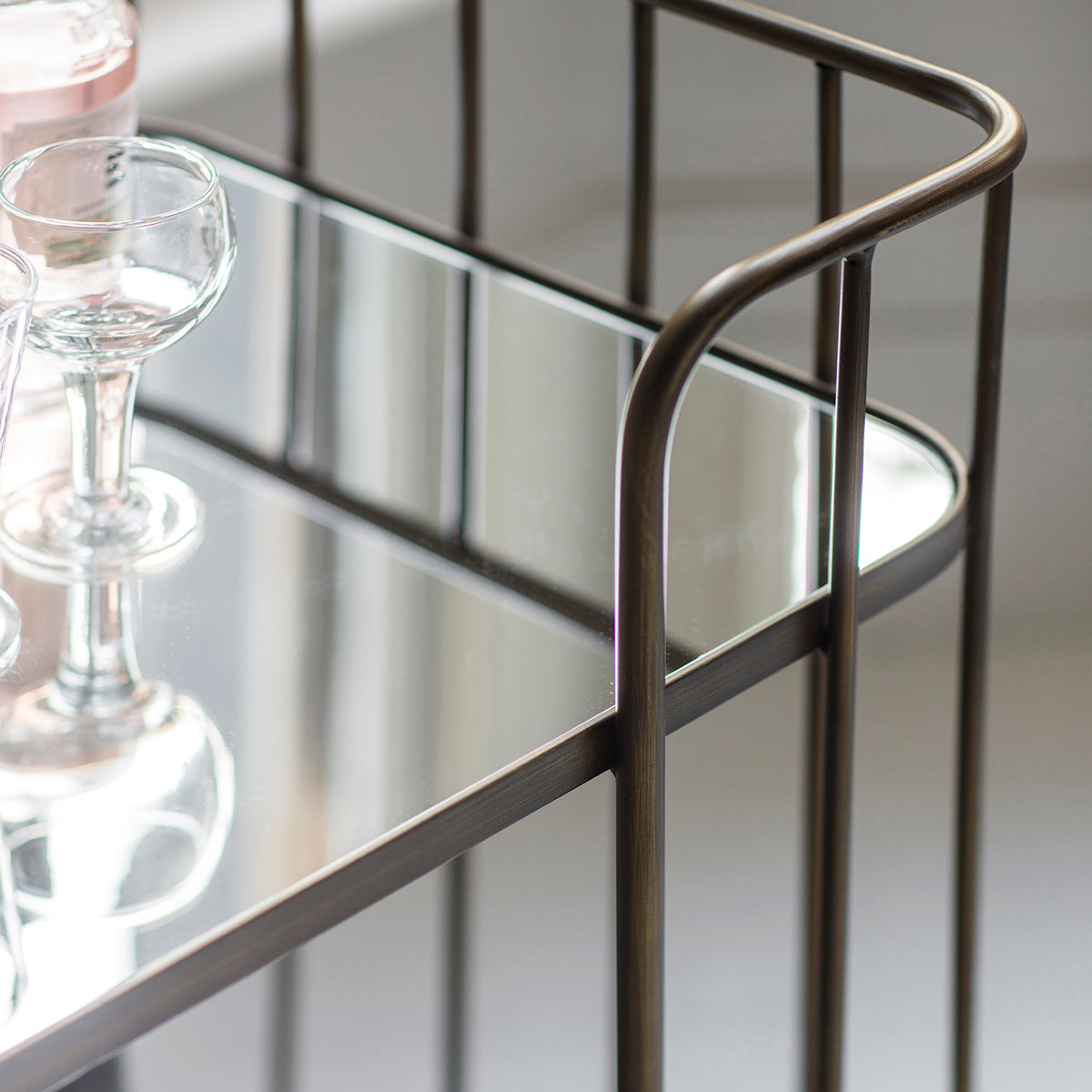 A bronze Verna drinks trolley with wine glasses, perfect for interior decor or home furniture.