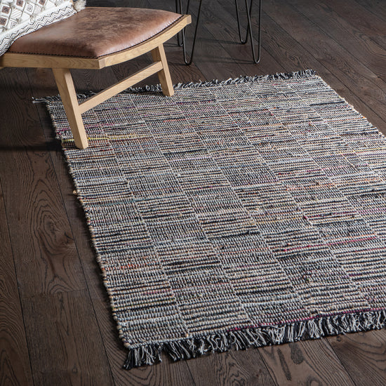 Load image into Gallery viewer, An Aveton Rug Multi 1200x1700mm with fringes on a wooden floor, perfect for interior decor.

