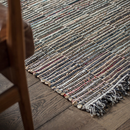 Load image into Gallery viewer, An Aveton Rug Multi 1200x1700mm by Kikiathome.co.uk enhances interior decor on a wooden floor.
