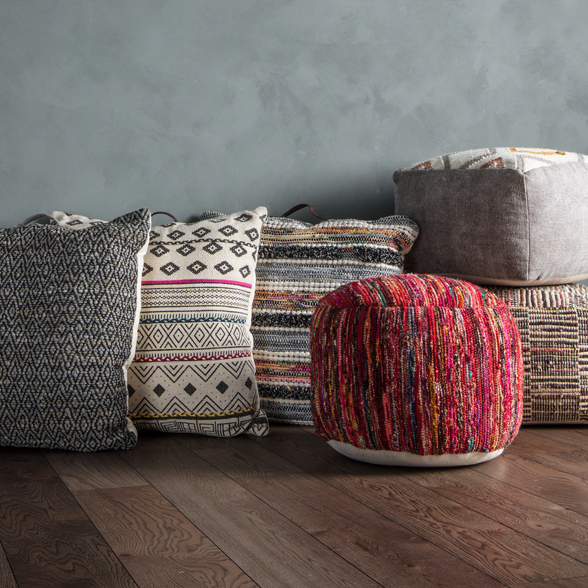 A group of Diaz Pouffe Multi pillows by Kikiathome.co.uk, adding a touch of interior décor to the wooden floor.