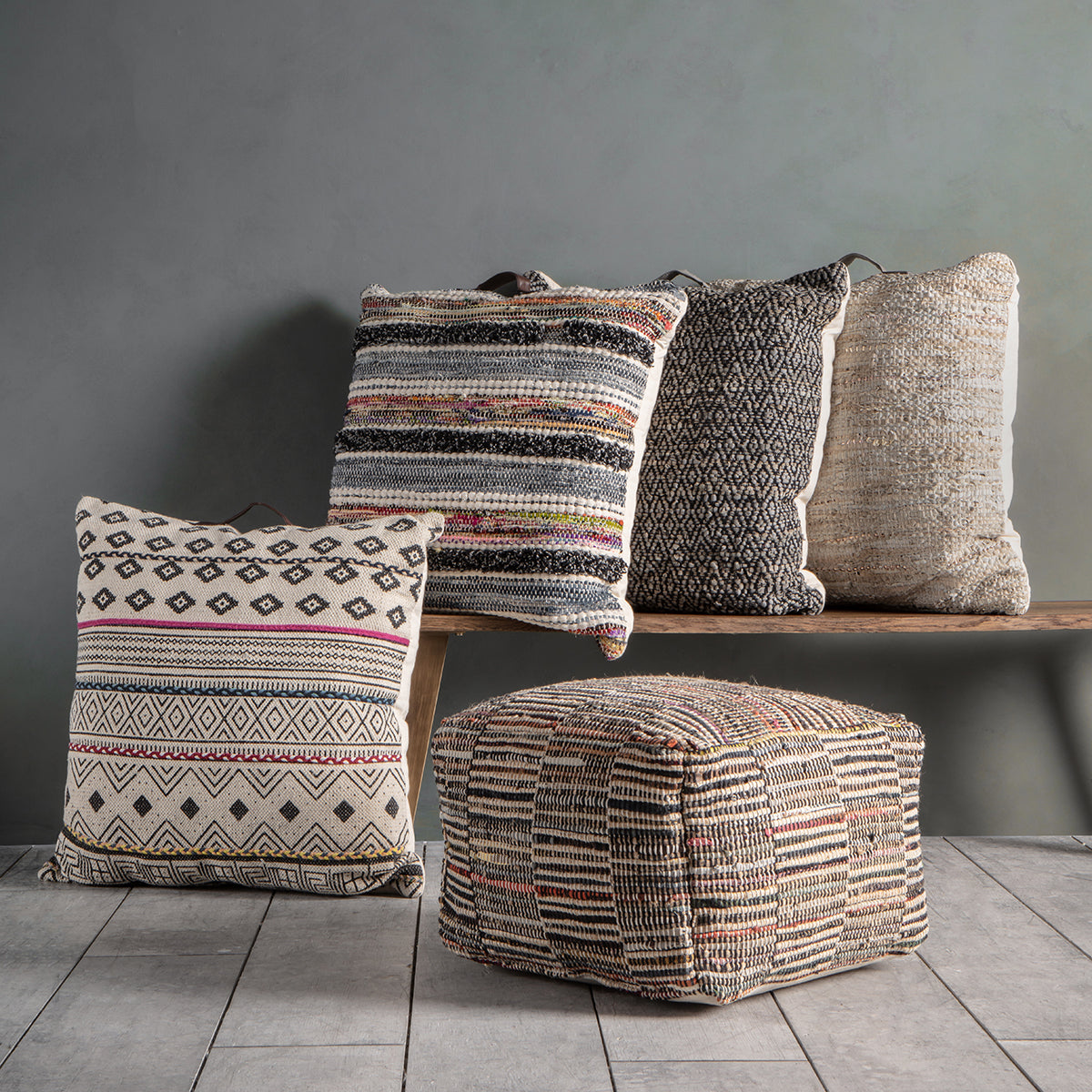 A collection of Aveton Pouffe Multi pillows arranged on a bench, adding a touch of interior decor to the home furniture setup.
