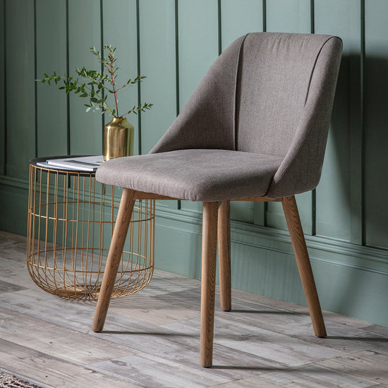 A Hempston Dining Chair Slate Grey (2pk) 570x610x840mm from Kikiathome.co.uk next to a green wall, perfect for home furniture and interior decor.