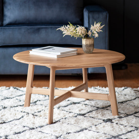 A stunning interior decor piece, this Dairy Round Coffee Table with a creative display of books and a vase enhances any home furniture arrangement.