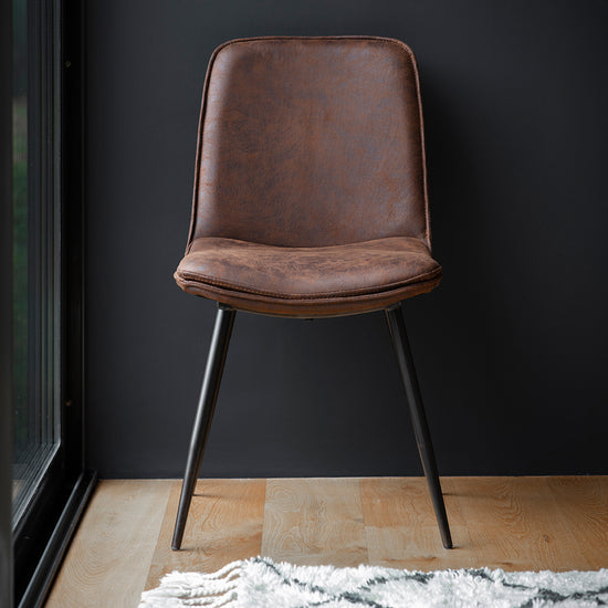 A Newton Chair Brown (2pk) by Kikiathome.co.uk complements interior decor against a black wall.