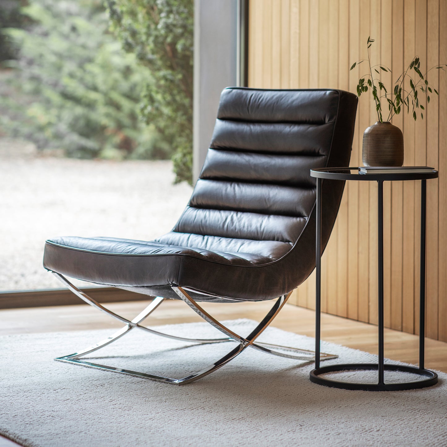 A black leather lounger from Kikiathome.co.uk placed in front of a window as home furniture.