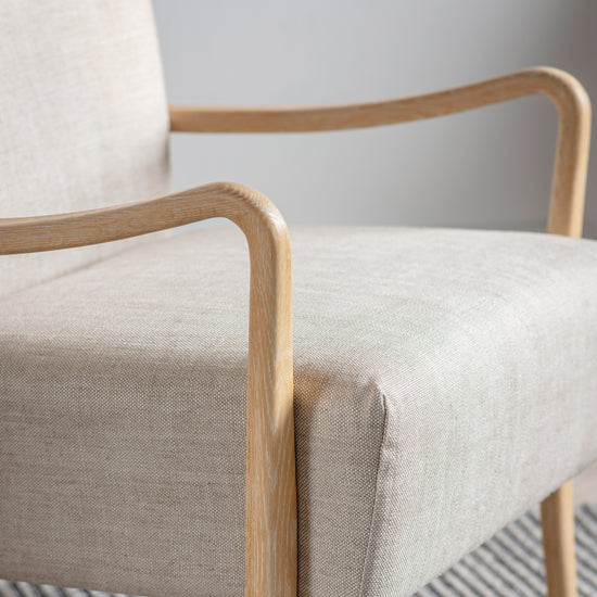 A Galmpton Armchair Natural Linen with wooden legs on a rug for home furniture and interior decor.