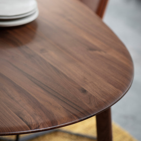A close up of a Walnut oval dining table from Kikiathome.co.uk with plates on it, perfect for interior decor and home furniture.