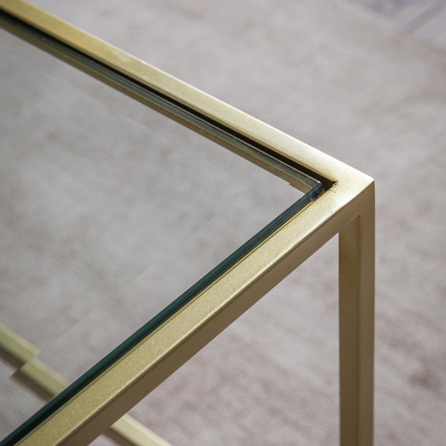 A close up of the champagne-colored Engleborne Coffee Table with a brass frame, perfect for home furniture and interior decor.