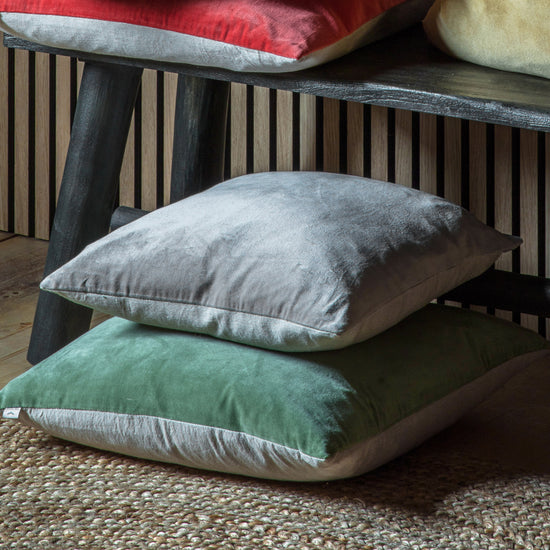 A group of Cotton Velvet Cushion Grey 500x500mm pillows stacked on top of a wooden bench, perfect for interior decor.