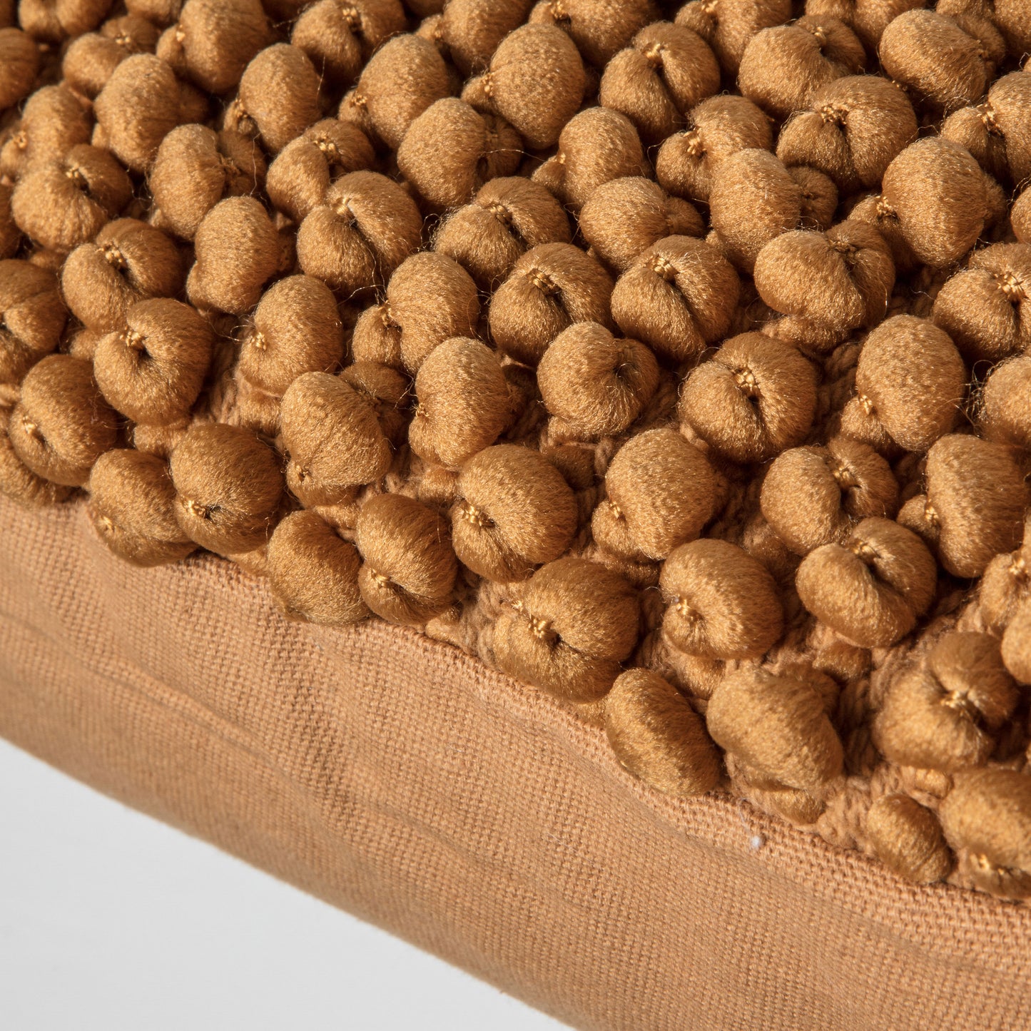A close up of a pile of brown Pino Cushion Tan 450x450mm pom poms for home decor from Kikiathome.co.uk.