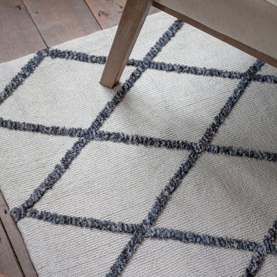 A Mayo Rug Cream Charcoal 800x1500mm with a black and white pattern on a wooden floor.