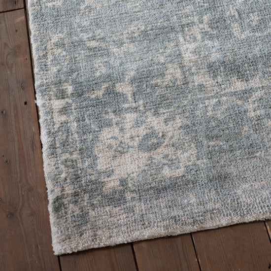 Load image into Gallery viewer, A dark teal Minott rug from Kikiathome.co.uk adds interior decor to a wooden floor.
