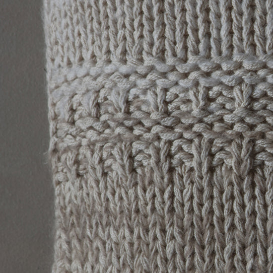 A close up of a 2 Tone Knitted Cushion Oatmeal Cream sweater for interior decor.