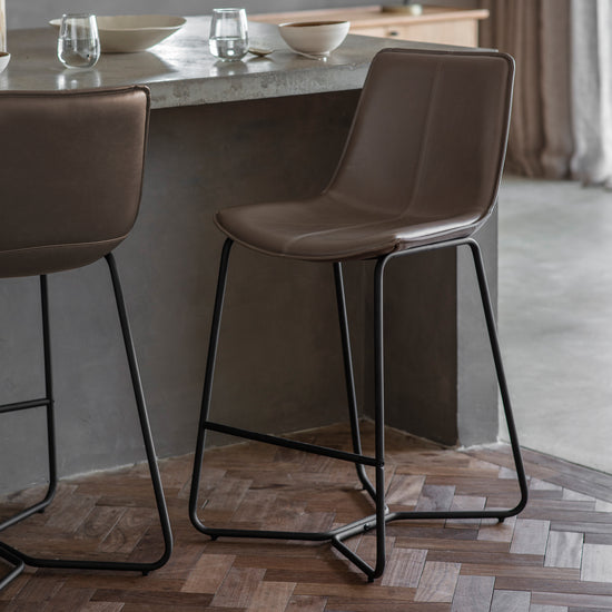 A pair of Slapton Stool Brister bar stools in brown leather, perfect for interior decor from Kikiathome.co.uk.