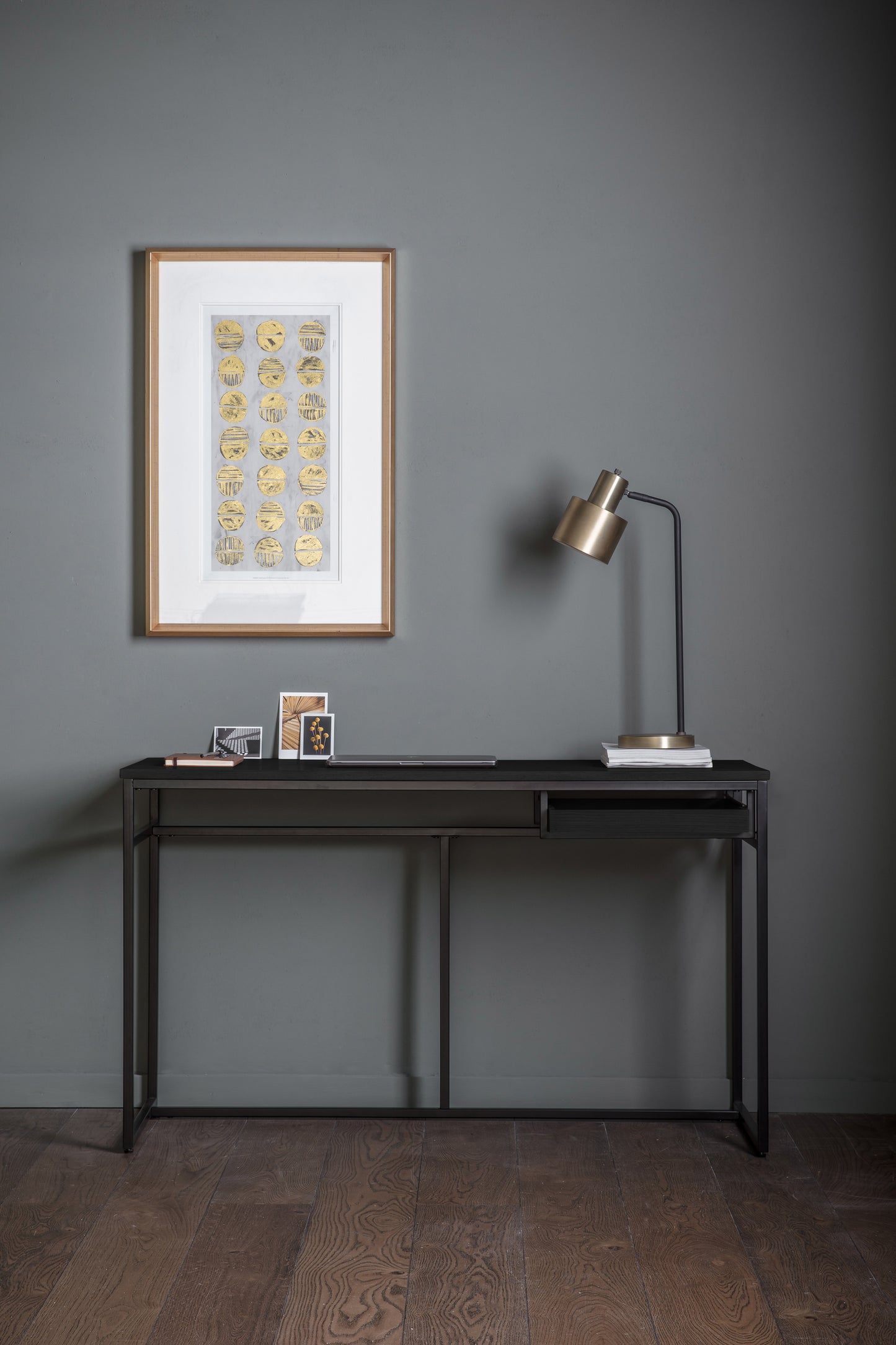 A Ringmore Desk Black 1300x500x760mm by Kikiathome.co.uk in a room with a painting on the wall, perfect for home furniture and interior decor.
