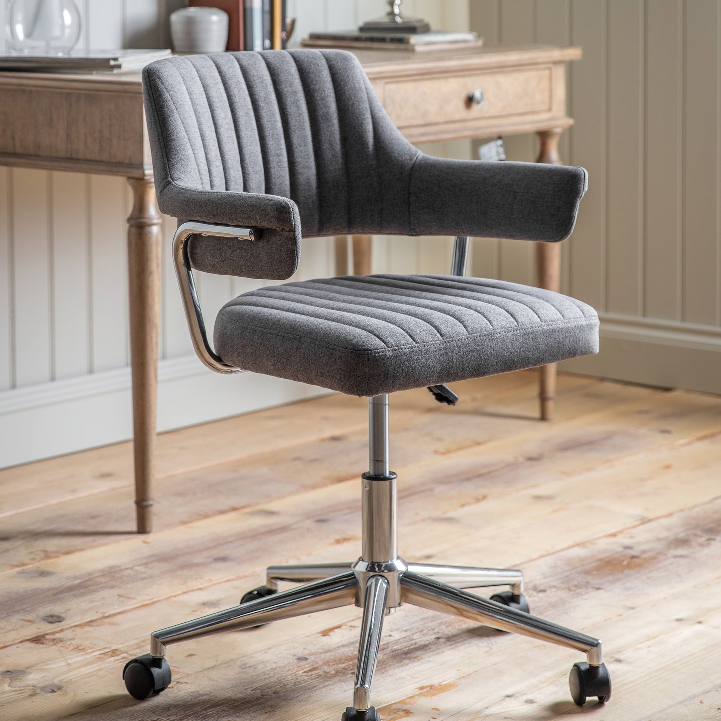 A Mcintyre Swivel Chair Charcoal from Kikiathome.co.uk on casters in front of a wooden floor, perfect for home furniture and interior decor.