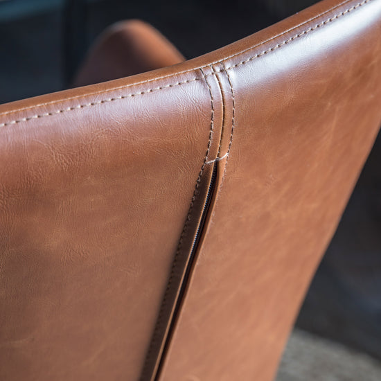 A close up view of a Noss Swivel Chair Brown leather chair, perfect for interior decor.