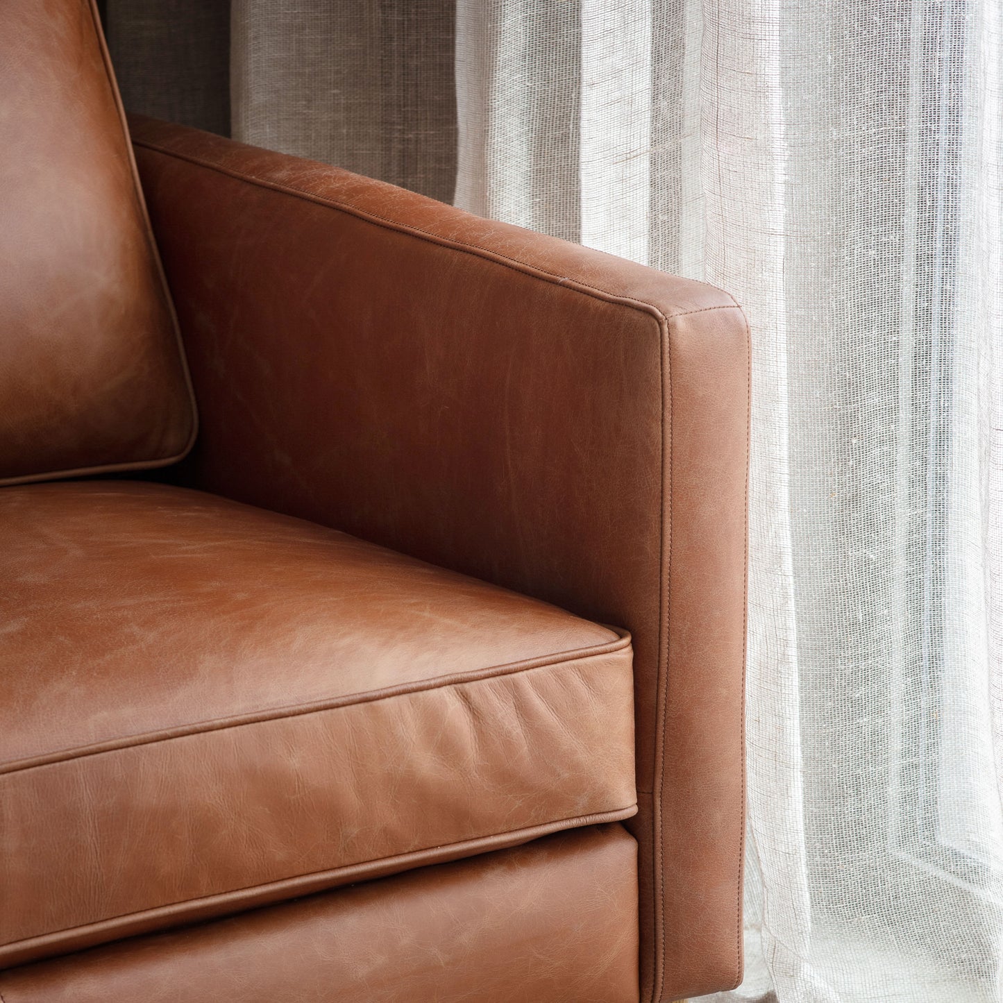 A Vintage Brown Leather Osborne 2 Seater Sofa by Kikiathome.co.uk adds interior decor to a home's furniture arrangement, positioned in front of a window.
