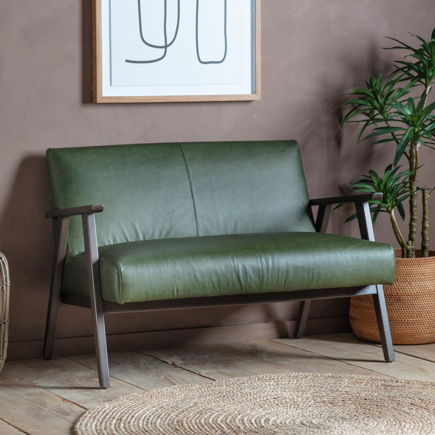 A Neyland 2 Seater Sofa Heritage Green Leather from Kikiathome.co.uk enhancing interior decor in front of a wall.