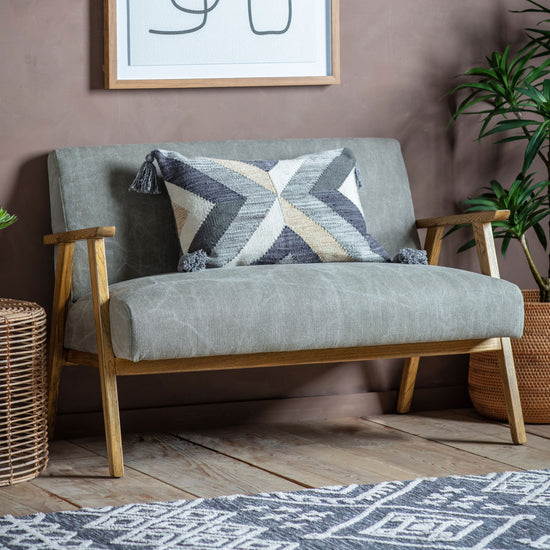 A Neyland 2 Seater Sofa in Pebble Linen offering comfortable seating, adorned with decorative pillows, and accompanied by a potted plant - an ideal piece for enhancing interior decor.