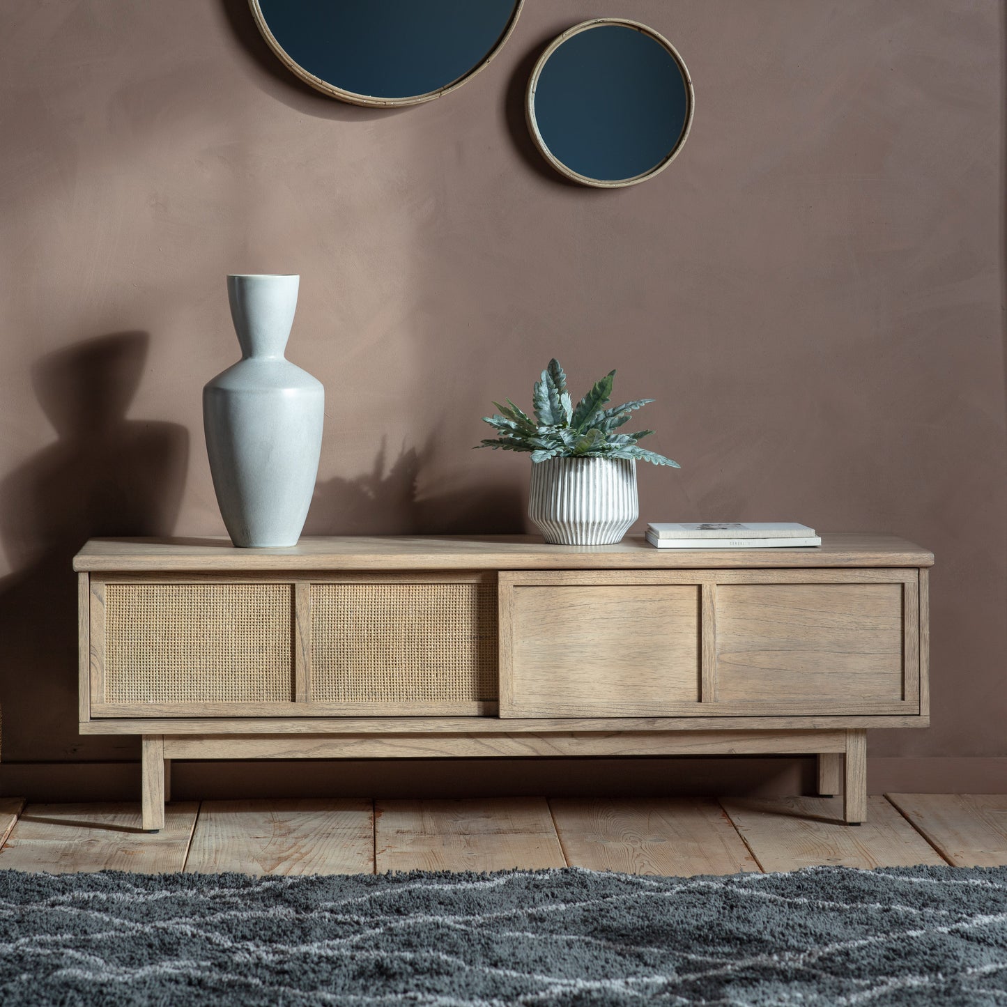 An Alvington Media Unit from Kikiathome.co.uk, an interior decor piece for home furniture, adorned with a plant and a mirror.