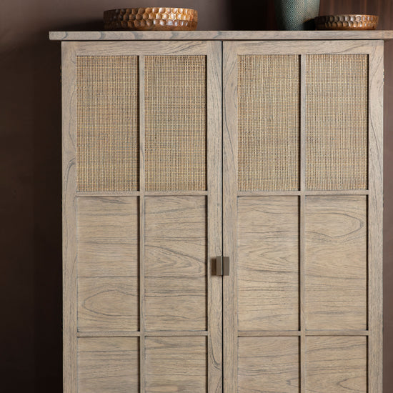 An Alvington 2 Door Cupboard with rattan doors and wicker baskets for interior decor.