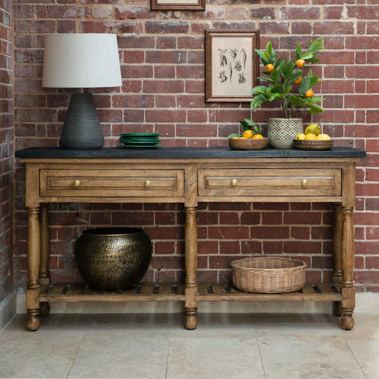 A 1690x490x870mm Halwell 2 Drawer Console by Kikiathome.co.uk for interior decor, showcased with a lamp in front of a brick wall.