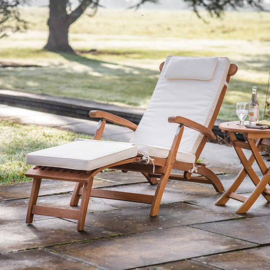 A Bickington Outdoor Lounger and table for home furniture on a stone patio.