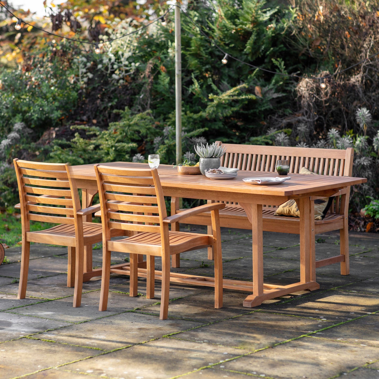 A Cornworthy Outdoor Ext Dining Table and chairs in a garden by Kikiathome.co.uk, ideal for interior decor and home furniture.