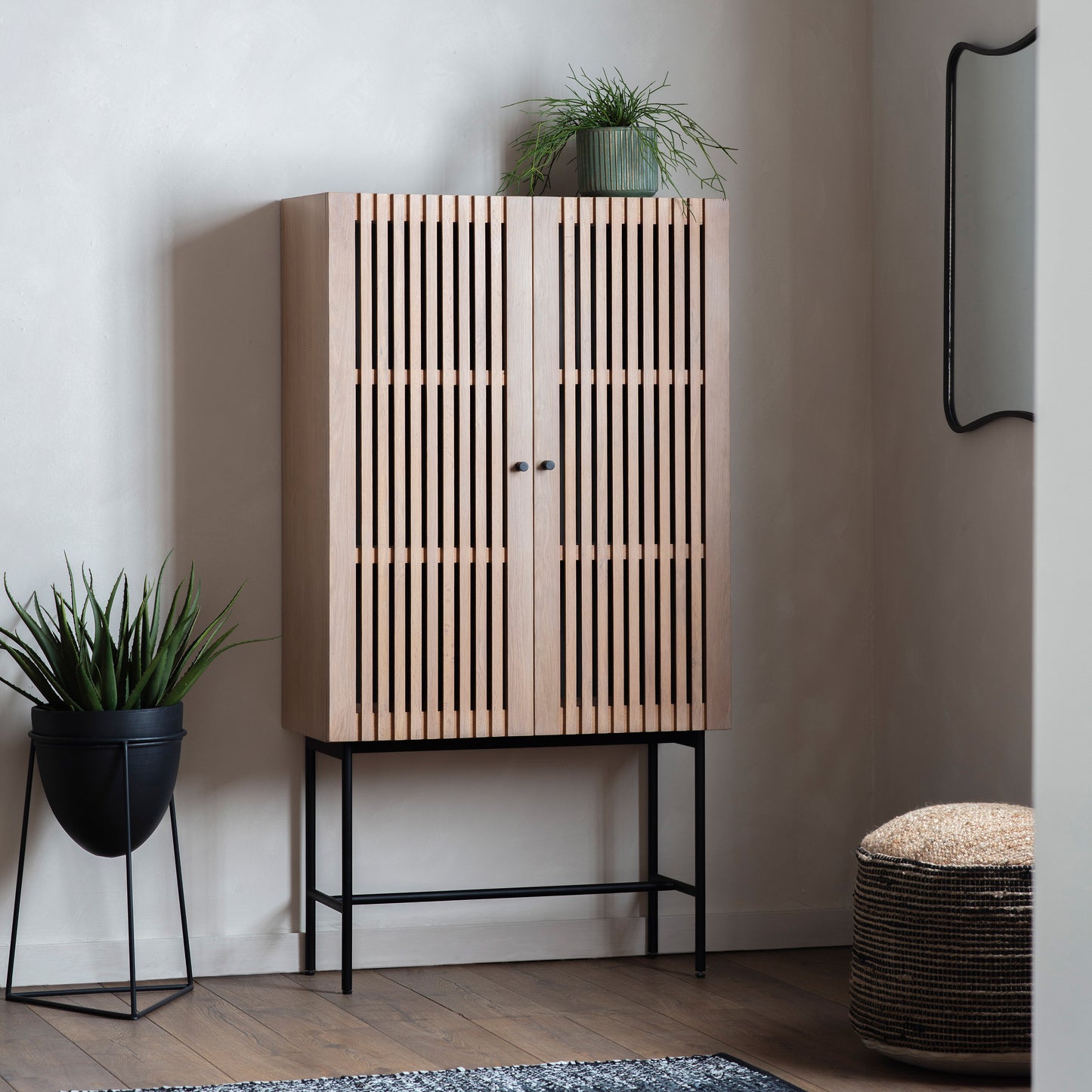 Load image into Gallery viewer, A Tortington cocktail cabinet with slats and a potted plant, perfect for interior decor.
