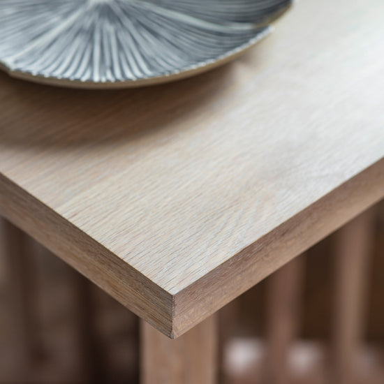A close up of the Tortington Dining Table, an interior decor and home furniture piece, with a plate on it.