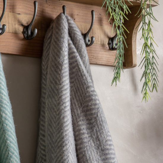 Two Wool Throw Grey 1300x1700mm towels hanging on hooks on a wall from a home furniture retailer.