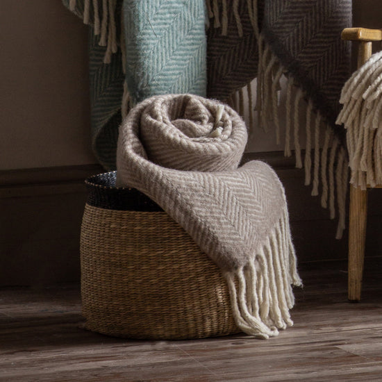Interior decor, Home furniture: A basket full of Wool Throw Taupe 1300x1700mm blankets on a wooden floor.