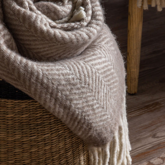 A Wool Throw Taupe 1300x1700mm by Kikiathome.co.uk in a wicker basket for interior decor.