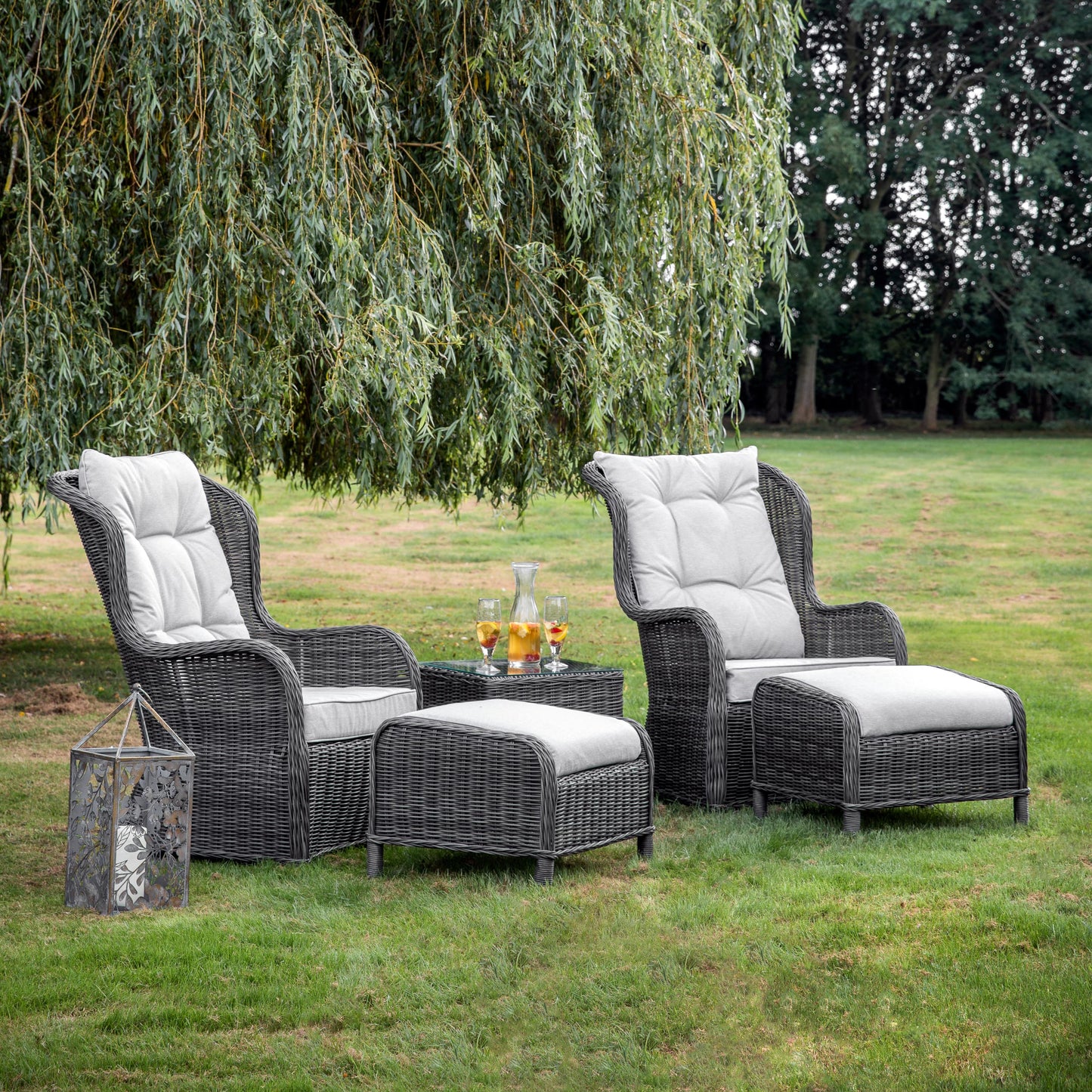 An interior decor item, the Otterton High Back Lounge Set Grey, is showcased in a grassy area on Kikiathome.co.uk.