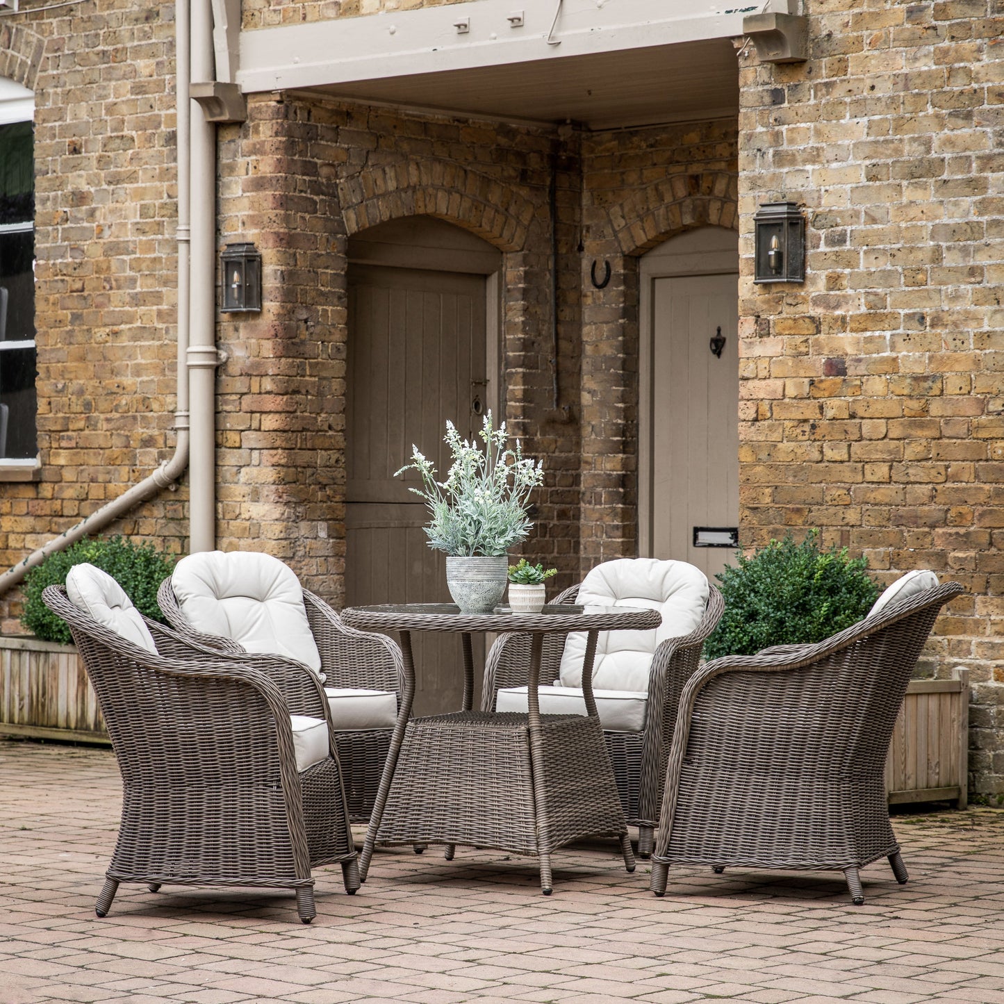 A Meavy 4 Seater Round Dining Set Natural by Kikiathome.co.uk enhancing interior decor in front of a brick building.
