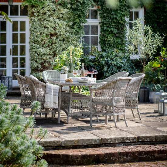 An Allington 6 Seater Oval Dining Set Stone by Kikiathome.co.uk, perfect for interior decor or home furniture, in a garden.