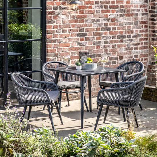 A Prawle 4 Seater Dining Set from kikiathome.co.uk showcased in a garden, perfect for interior decor.
